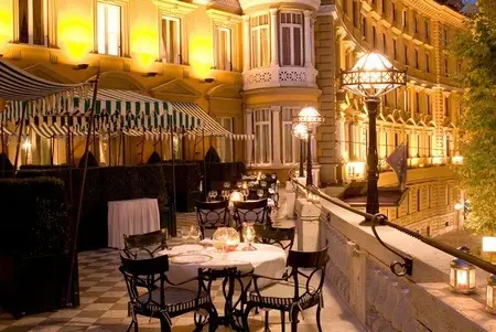 Terrazza dell’albergo con tavoli apparecchiati e facciata illuminata sullo sfondo