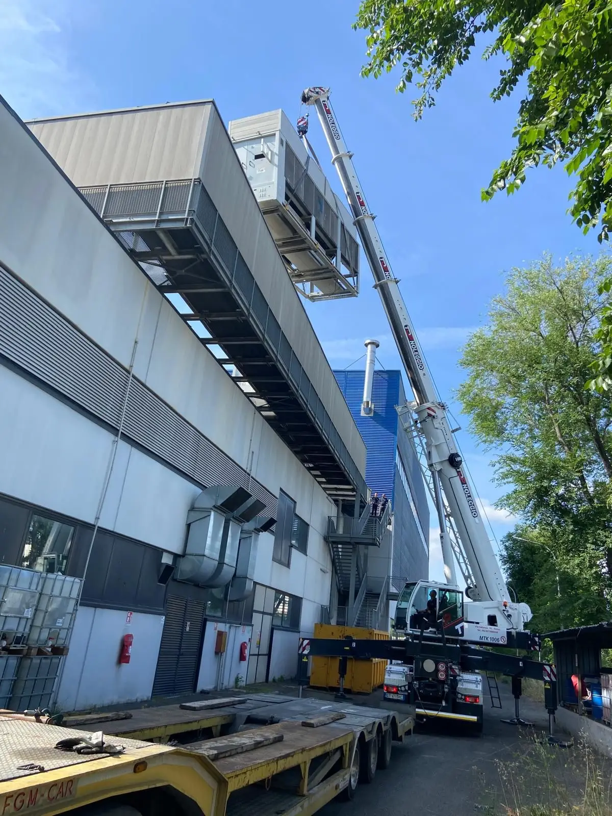 Autogrù al lavoro lungo il prospetto dello stabilimento