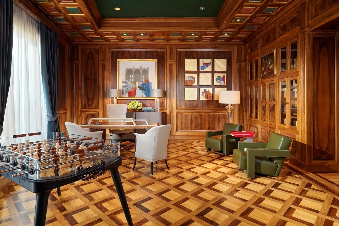Sala della suite con boiserie in legno, parquet a disegno e tavolo da gioco